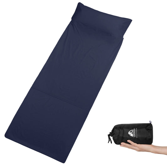 Navy blue cotton sleeping bag liner displayed next to its black packable carrying case, held in a person's hand.
